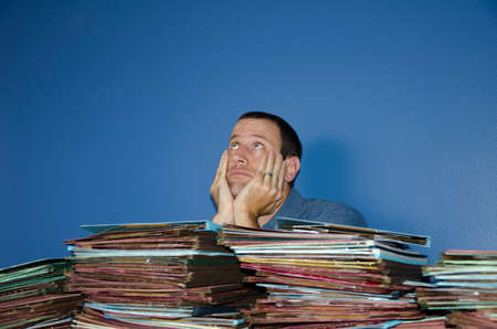 Man looking bored and stressed at work with his hands on his face looking up at the ceiling.の写真素材