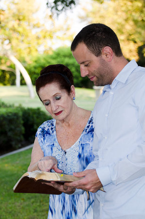 Mother and adult son reading the Bible together.