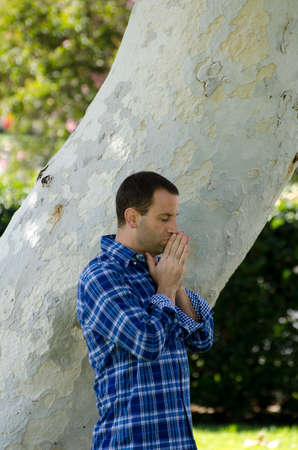 Young man praying in a park.の写真素材