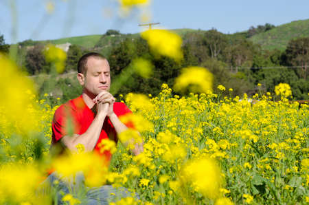 Man praying hidden in a field of yellow flowers.の写真素材