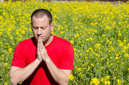 Man praying alone in a field of yellow flowers.の写真素材