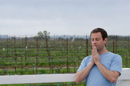 Man praying in front of farmland alone.の写真素材