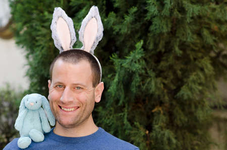 Celebrating Easter! Man with bunny ears and a bunny stuffed animal on his shoulder.の写真素材
