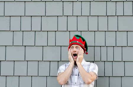 Surprised man with hands on his face wearing a Christmas hat.の写真素材
