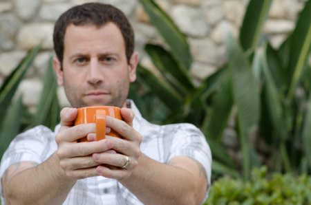 Man holding coffee mug with mug in focus and man out of focus.の写真素材