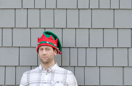 Man in a Christmas hat looking to the side with a smirk.の写真素材