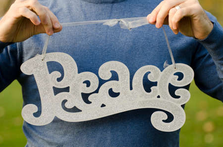 Peace at Christmas! Man holding a Peace sign, holding torso and hands are showing no face.の写真素材