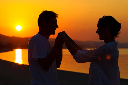 Couple in love holding hands on seashore at sunset, Romantic marriage proposal on the sea shore, Photographyの写真素材