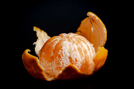 Half peeled mandarin on a black background close-upの写真素材