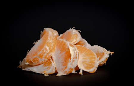Half peeled mandarin on a black background close-upの写真素材