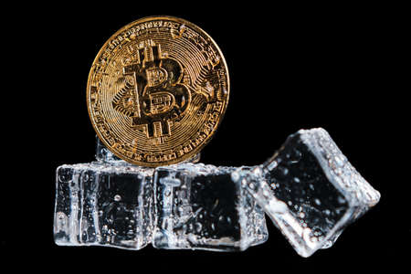 Bitcoin coin among ice cubes in drops of water on a black background 2020の写真素材