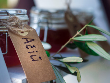 Small glass jars filled with honey, decorated with eucalyptus and a writing attached to them saying