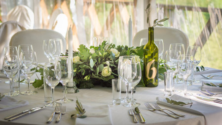 Decorated wedding tables with numbers on bottles and beautiful rose compositions on the tablesの写真素材