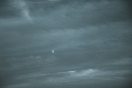 On a night when the moon is shining, it can still be visible even amidst a cloudy sky, creating a beautiful atmospheric sceneの写真素材