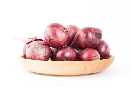 Bunch of red onions on wooden plate isolated on white backgroundの写真素材