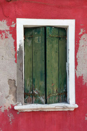 Picturesque old window with green shutters on red wall (Burano island, Venice, Italy)の写真素材