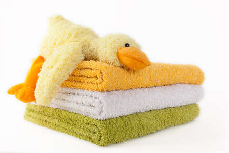 Three colorful towels with yellow plush duck isolated on white backgroundの写真素材