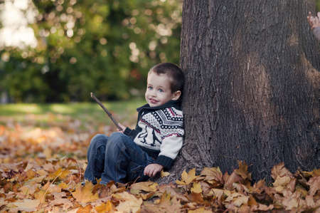 3 years old child sitting on the golden leafの写真素材