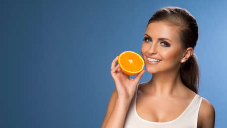 Portrait of a young beautiful woman with orangeの写真素材