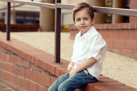 Small  happy boy sitting on the stone wallの写真素材