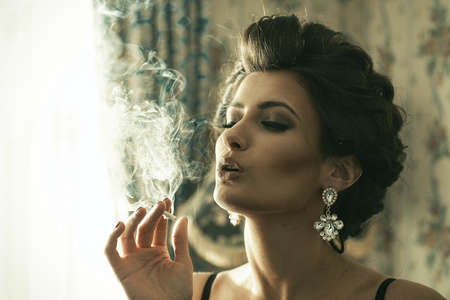 Elegant brunette woman smoking a cigaretteの写真素材