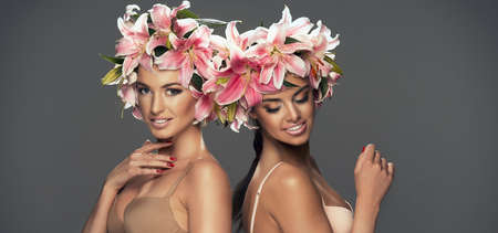 Two beauty smiling girls with flowers in hairの写真素材