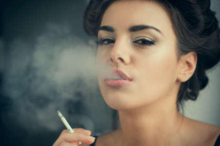 beautiful brunette woman smokes at homeの写真素材