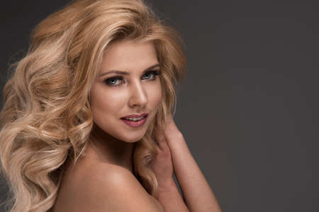 Sensual beautiful blonde woman posing with long curly hair.の写真素材
