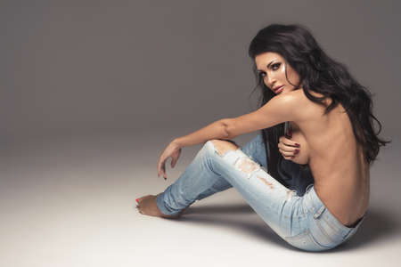 Sexy attractive brunette woman posing only in jeans in studioの写真素材