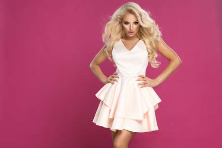 Beauty blonde woman wear pink dress, over pink wallの写真素材
