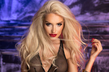 Sexy blonde woman over black background with colourfull lightの写真素材