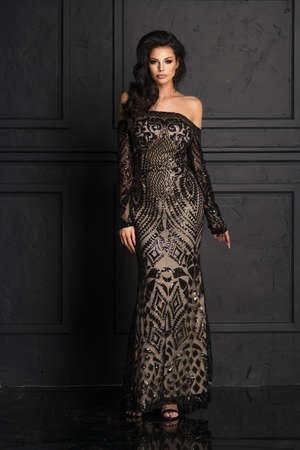 Sensual beautiful brunettee woman posing in long black dress. Girl with long curly hair.の写真素材