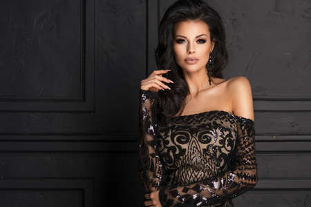 Sensual beautiful brunettee woman posing in long black dress. Girl with long curly hair.の写真素材