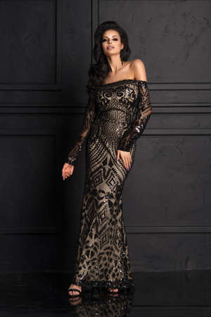 Sensual beautiful brunettee woman posing in long black dress. Girl with long curly hair.の写真素材