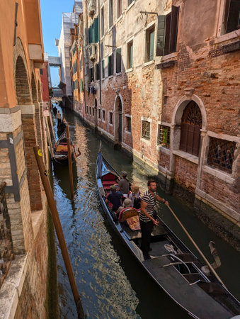 A captivating scene of a small canal in Venice, Italy, featuring gondolas and traditional wooden posts. This picturesque destination is a must-see for travelers seeking Venices unique charmの写真素材