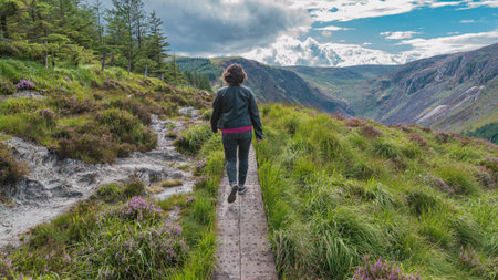 Woman is walking on the trail on top of the mountain in the valley of Glendalough, Wicklow...