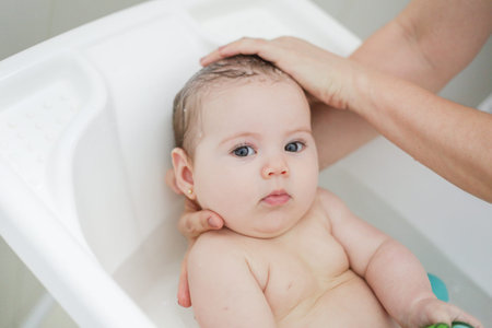 Mother washing her baby in bathtub. Shallow depth of field