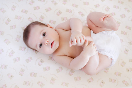 Portrait of a cute baby girl lying on the bed and looking at camera