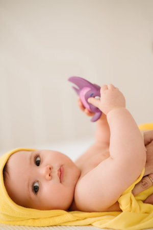Portrait of a newborn baby girl in a yellow towel with a pacifier
