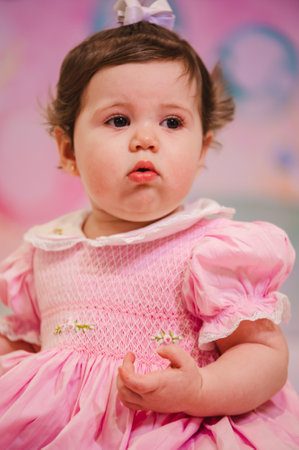 Beautiful baby girl in a pink dress on a colorful background.の写真素材