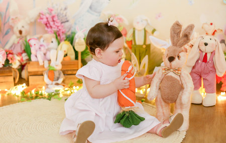 Cute baby girl in a pink dress with a toy bunny.