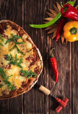 Homemade pizza on a wooden background. Top view. Bell pepper and chili pepper. Wine cork and corkscrew.の写真素材