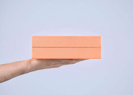 Pink gift box in mans hand. Pastel colors. Purple background.の写真素材