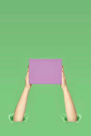 Purple gift box in female hands. Ink splashes. Pastel colors. Copy space for text.の写真素材