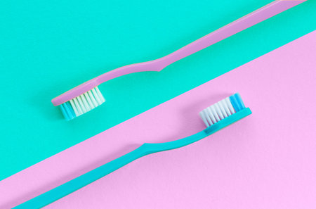 Toothbrushes on pink and turquoise background. View from above.