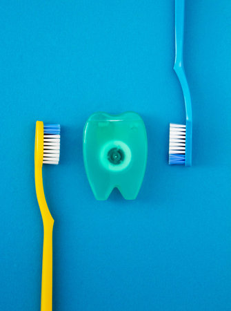 Toothbrushes and dental floss on blue background. Trendy health care concept.