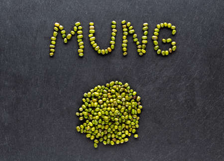 Dried green mung beans on dark stone background. Flat lay.の写真素材
