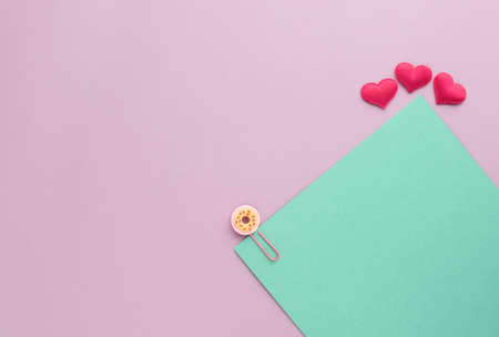 Turquoise sheet of paper with a paper clip and hearts on a pink background. Valentine concept. Minimalismの写真素材
