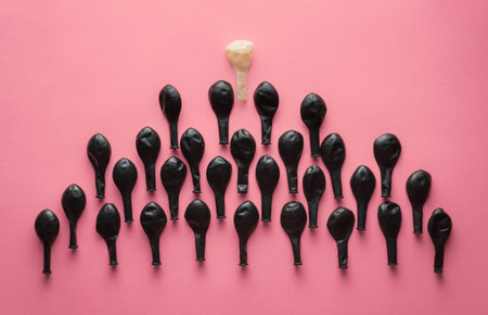 Blown black air balls in the shape of a triangle with a white ball on top on pink background....