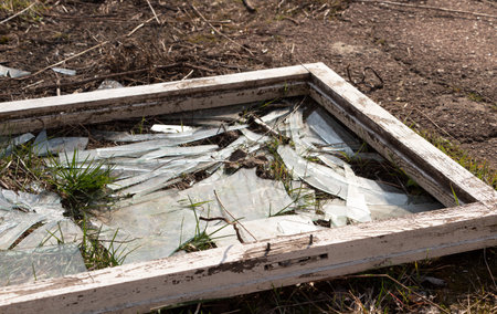 Window frame with broken glass with shards lies on the ground. Broken window.